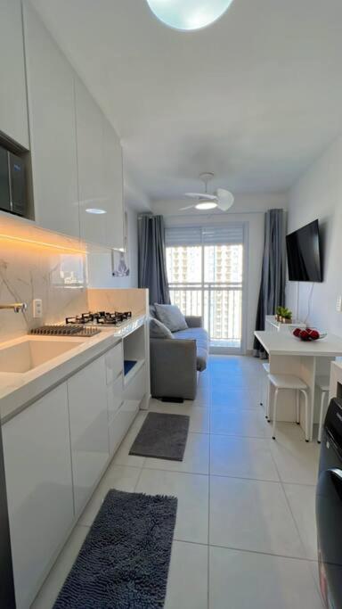 uma cozinha com armários brancos e uma sala de estar em Chácara Santo Antônio 1 dormitório com sacada em São Paulo