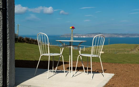 a table with two chairs and a table with a vase on it at Stable Cottage - Kinbane Self Catering Cottages in Ballintoy