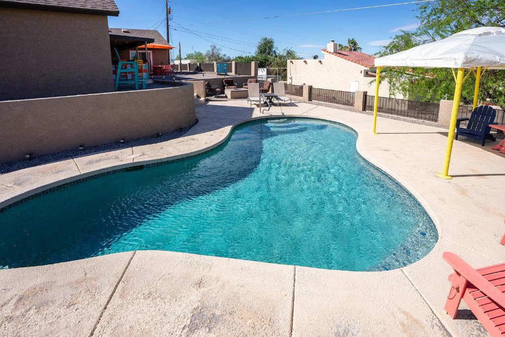 una piscina en un patio con sombrilla en Modern Desert Delight! 4- bedrooms, pool, gameroom en Lake Havasu City