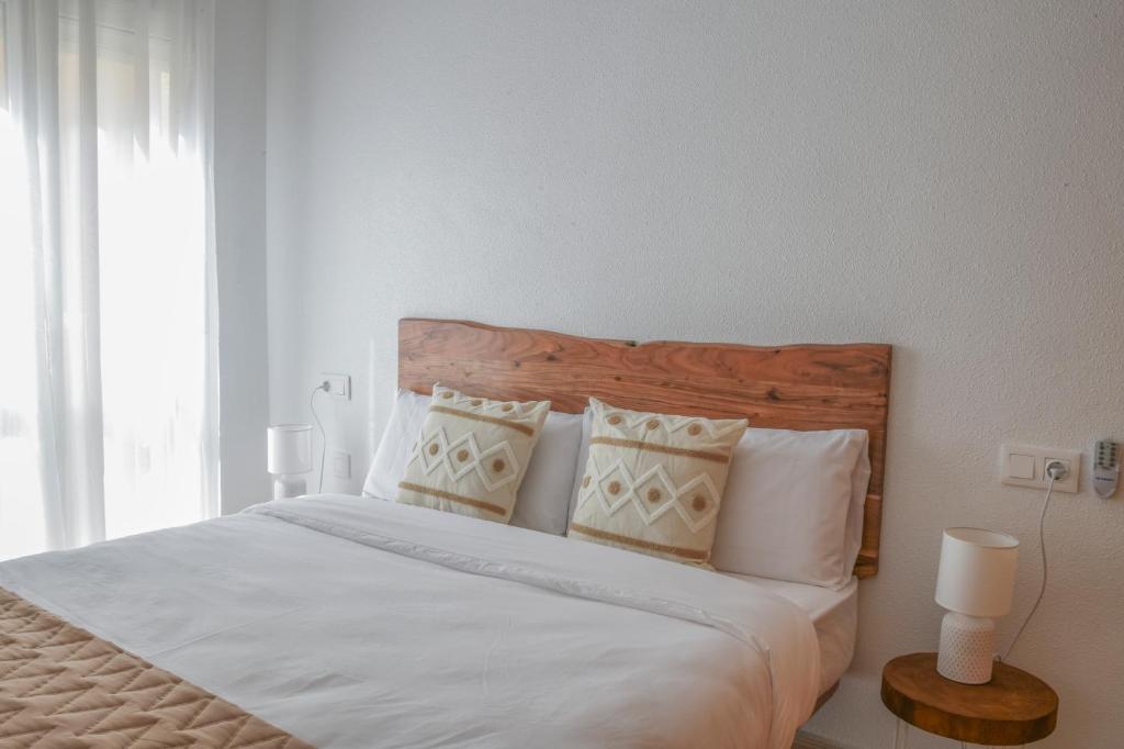 um quarto com uma cama grande com lençóis brancos e almofadas em Apartamento Las Brisas, Atico em Puerto de Mazarrón