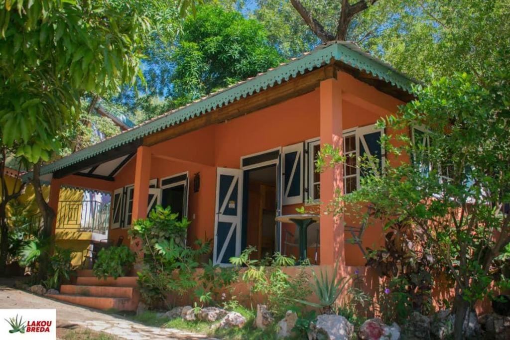 uma pequena casa laranja com uma árvore em Lakou Breda em Cabo Haitiano