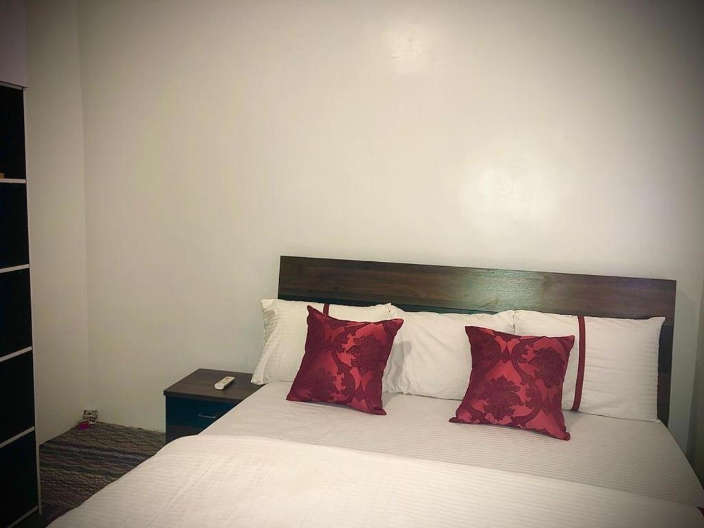 ein Schlafzimmer mit einem Bett mit roten Kissen in der Unterkunft willy-richy Apartments in Ikeja