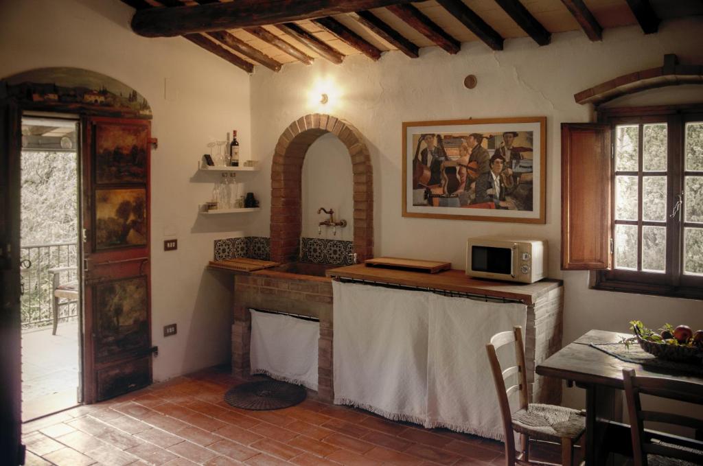 a kitchen with a fireplace and a table with a microwave at Il Bosco del Lebbio in Montaione