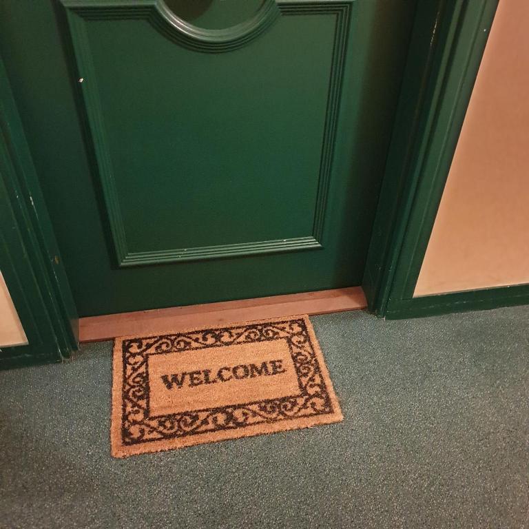 a welcome mat in front of a green door at Beautiful apartment * parking* Disneyland 10 min in Montévrain