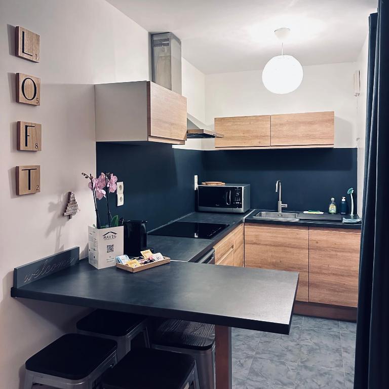 a kitchen with a black counter top and wooden cabinets at Beautiful apartment * parking* Disneyland 10 min in Montévrain