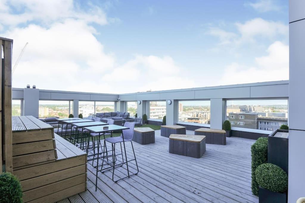 a rooftop deck with tables and chairs on a building at Lovely apartment in the centre of Croydon in Croydon
