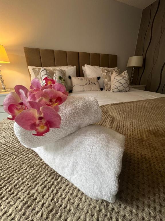 a bedroom with a bed with towels and flowers on it at Home from home The Orchid with Hot tub in Colnbrook