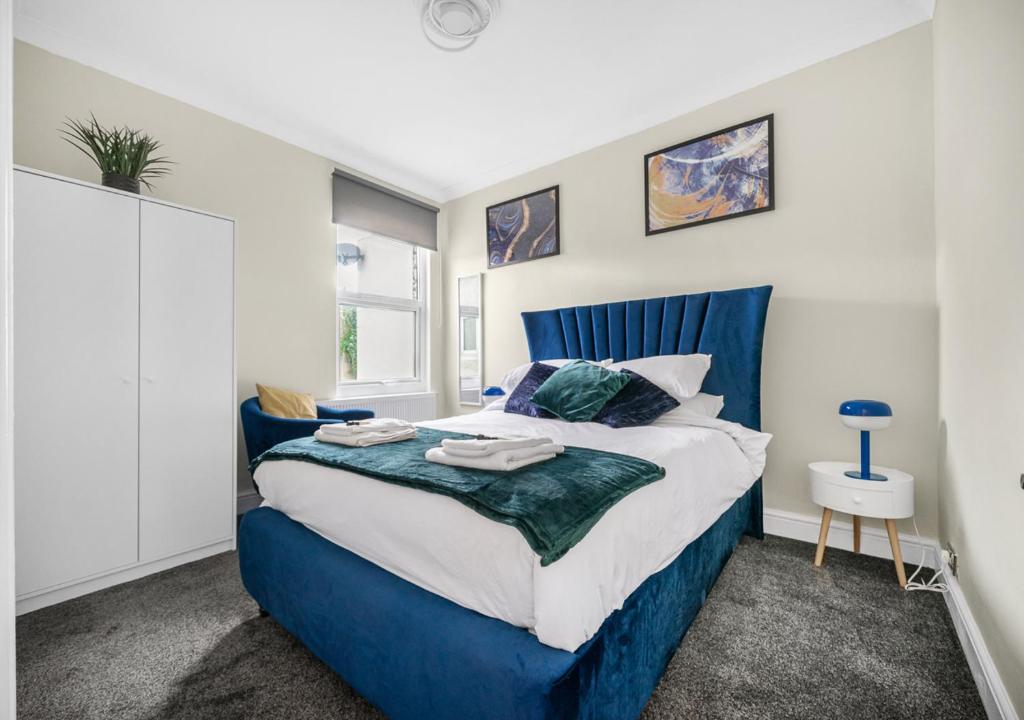 a bedroom with a blue and white bed and a window at Uksas Two bed Flat Free Parking in London