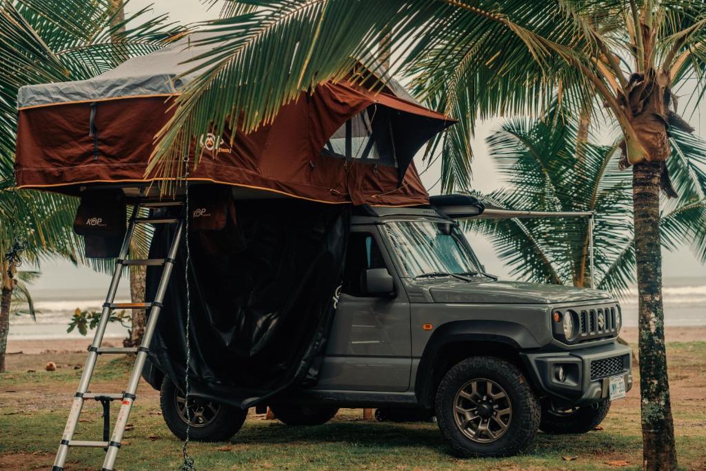 a gray jeep with a tent on top of a palm tree at 4BOX4 - 4x4 Car Rentals Only - SJO Airport in Santiago Este