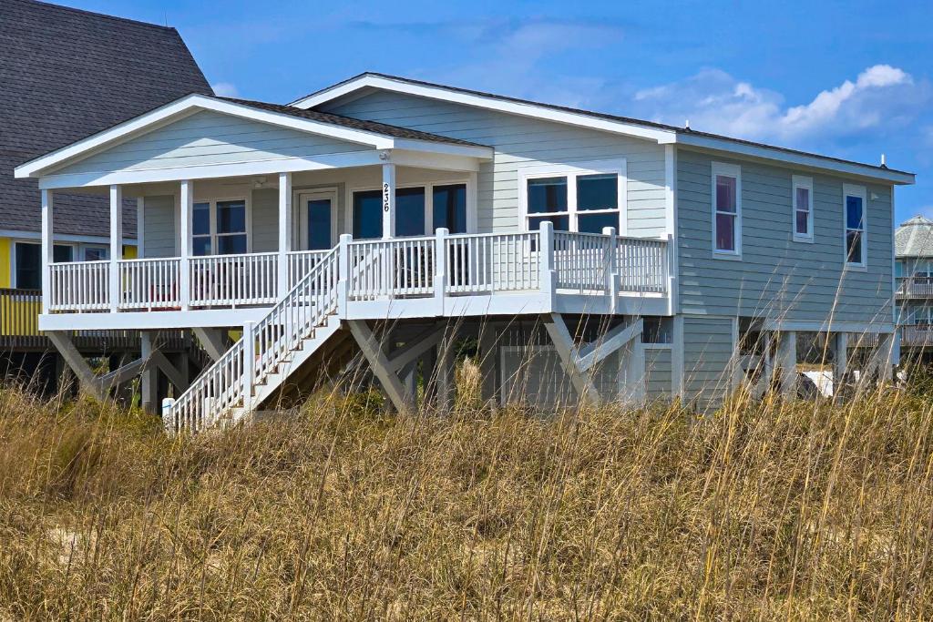 a blue house with a deck on the beach at HB21 Austin Cottage in Holden Beach