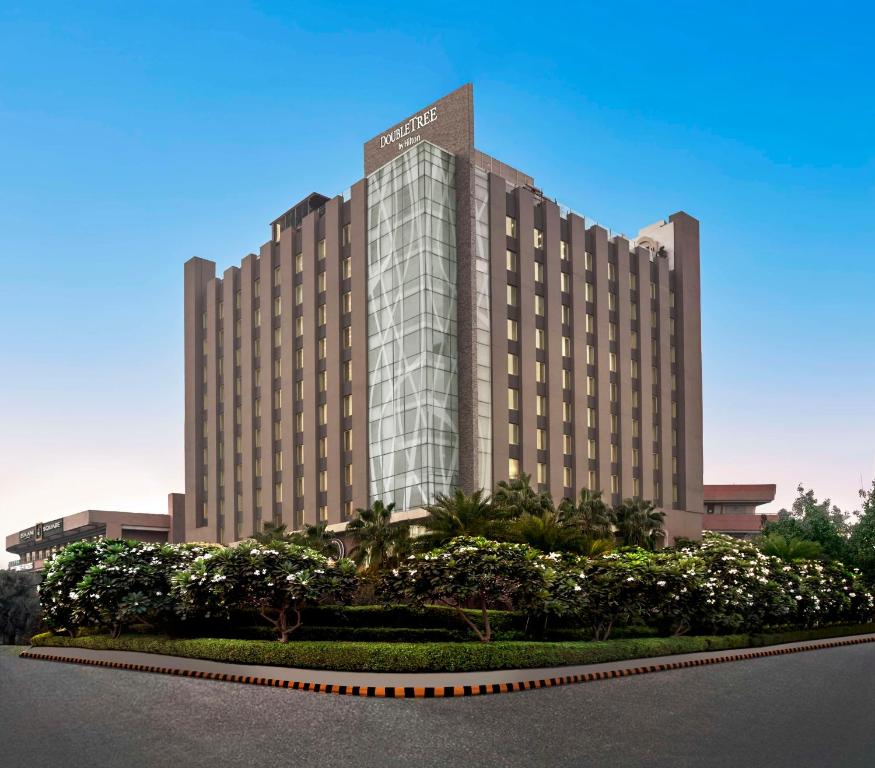 um grande edifício de hotel com árvores em frente em DoubleTree by Hilton Gurugram Baani Square em Gurgaon