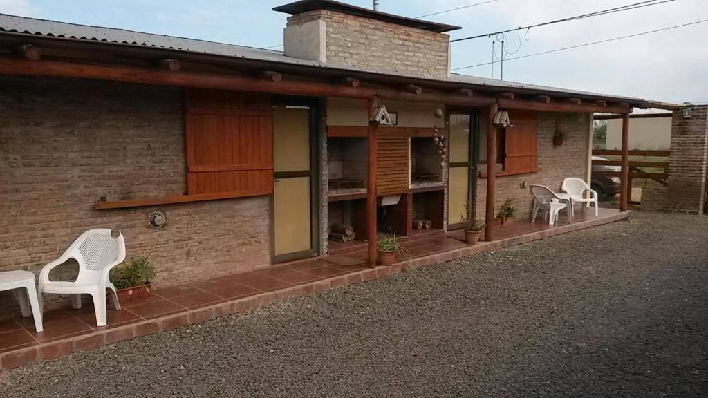 une maison avec des chaises blanches assises sur une terrasse couverte dans l'établissement Cabañas en La Gloria, à Villa Elisa
