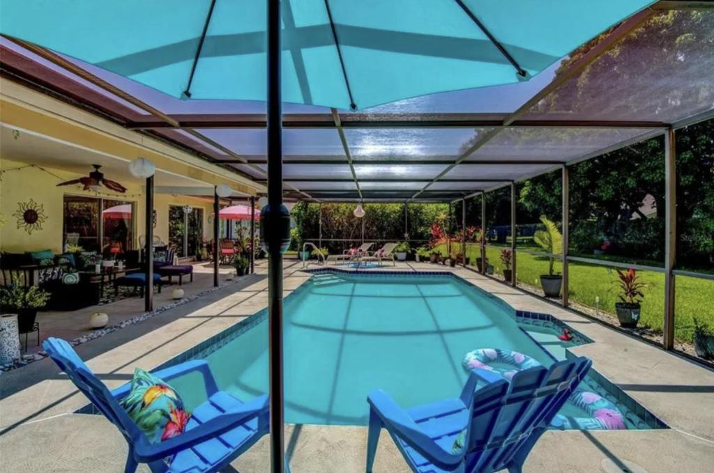 a swimming pool with two chairs and an umbrella at Cozy Pet-Friendly Private Pool Near Beaches in Bradenton