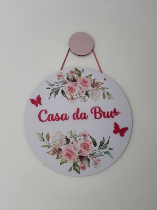um sinal que diz casa da burjit com flores cor-de-rosa em Casa da Bru pertinho da praia e da lagoa em Rio das Ostras