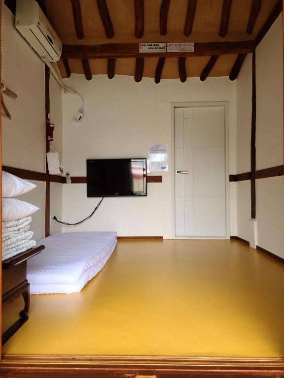 ein Schlafzimmer mit einem Bett und einem Flachbildfernseher in der Unterkunft Hanok Raon in Gyeongju
