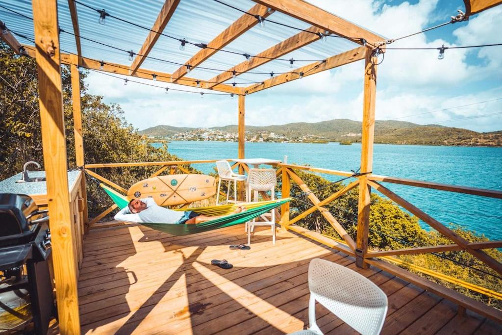 a person laying in a hammock on a deck overlooking the water at Ocean Front Villa 4 Studio in Culebra