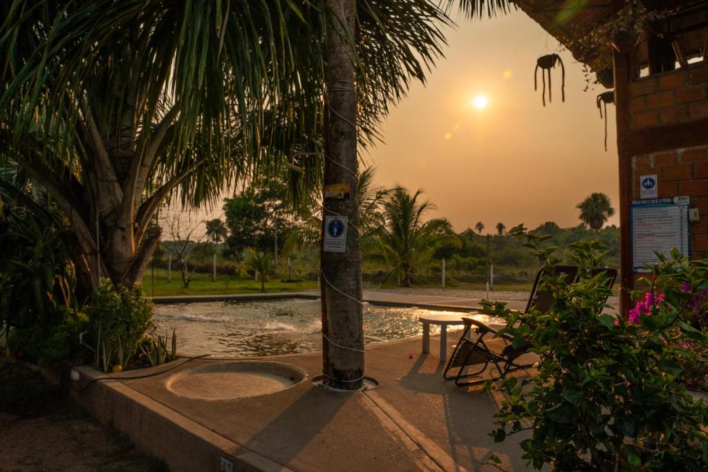 una palmera con una mesa y una puesta de sol en el fondo en Posada Campestre Ecoturística Granja Julieth, en San José del Guaviare
