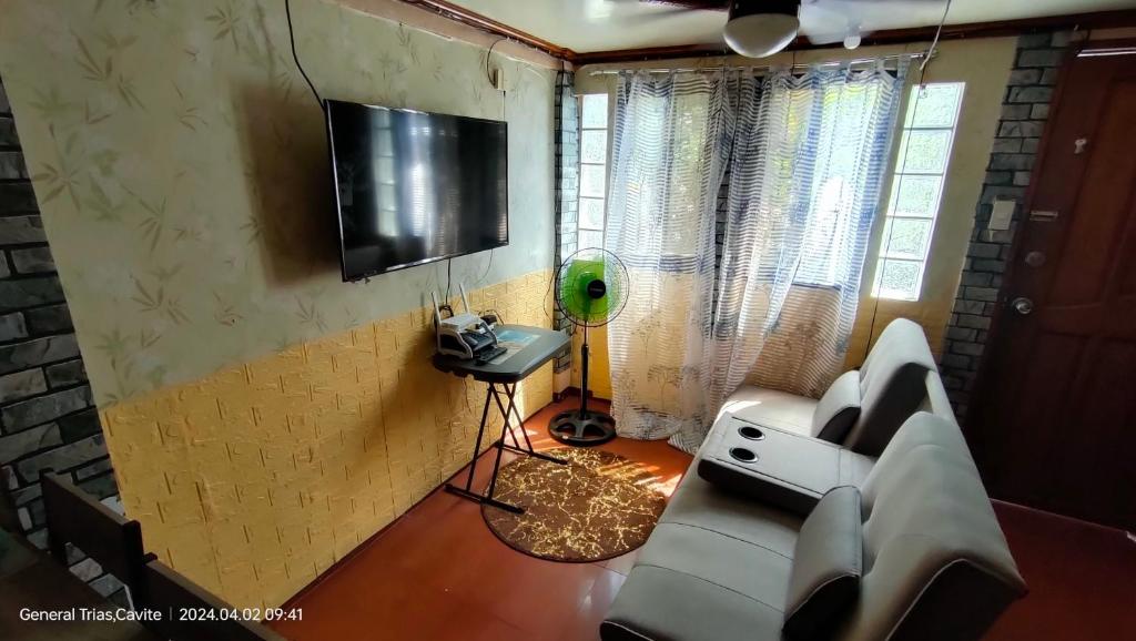 sala de estar con sofá y TV en la pared en 3Js Place 30-mins from Tagaytay, en General Trias