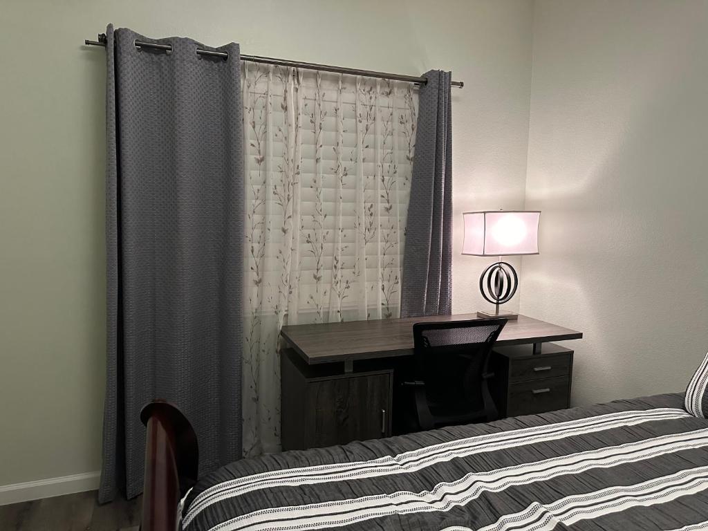 - une chambre avec un bureau, un lit et un rideau dans l'établissement Cozy private rooms in Eastvale, à Eastvale