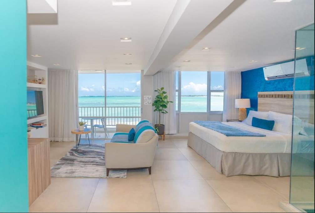 a bedroom with a bed and a balcony with the ocean at Modern Jewel Beachfront Isla Verde in San Juan
