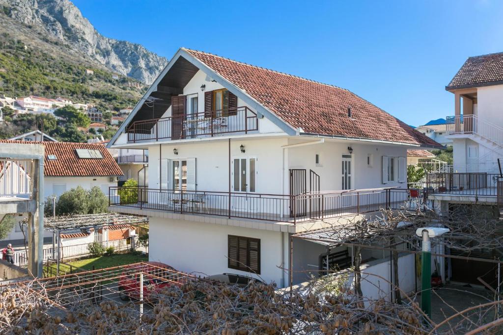 a white house with balconies and a mountain at Apartments by the sea Podaca, Makarska - 2783 in Podaca