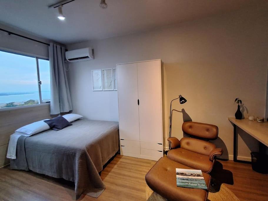 a bedroom with a bed and a chair and a desk at Vista Guaíba e Cais Embarcadero in Porto Alegre