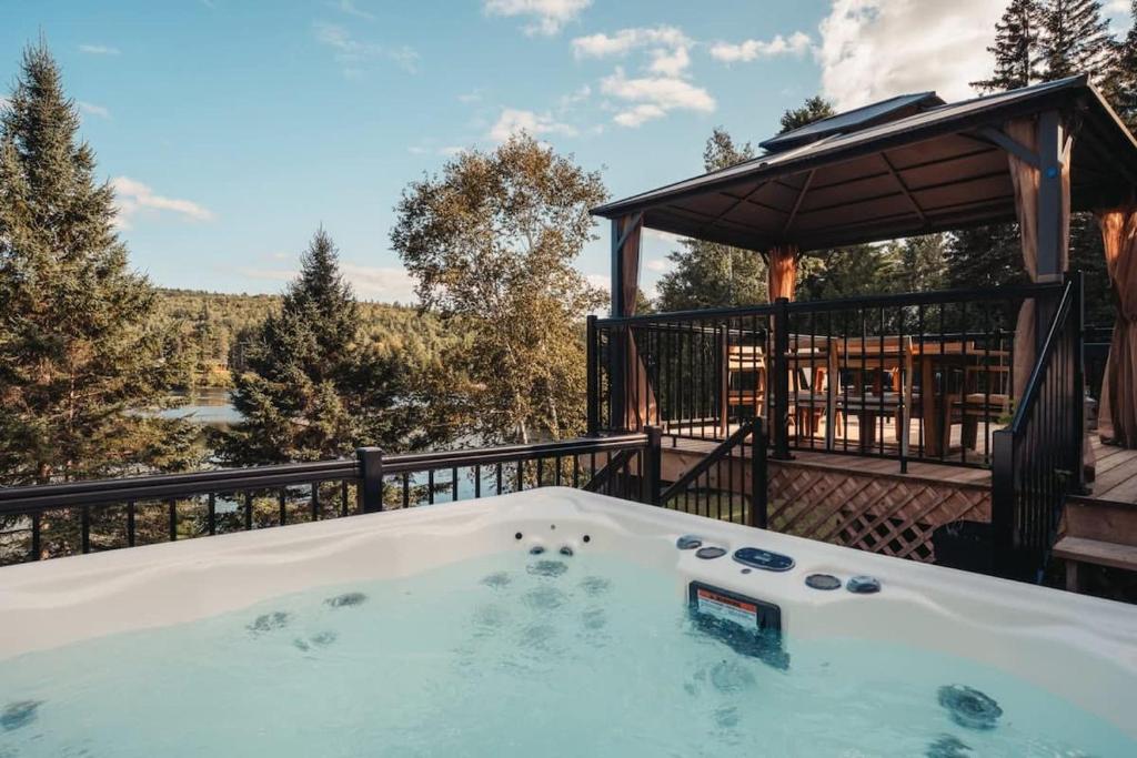 a hot tub on a deck with a gazebo at Magnifique chalet au bord du lac avec Spa in Saint-Alexis-des-Monts