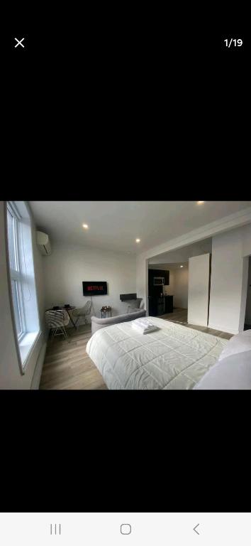een slaapkamer met een groot wit bed en een raam bij Le Bon Plan in Montreal