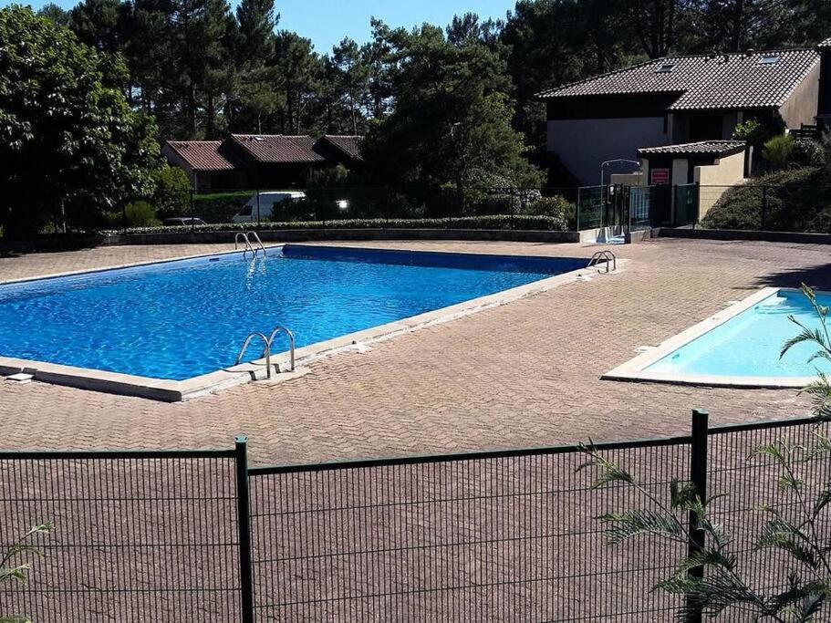 une grande piscine à côté d'une clôture dans l'établissement Maison d'été familiale, piscine dans la résidence, à Lacanau