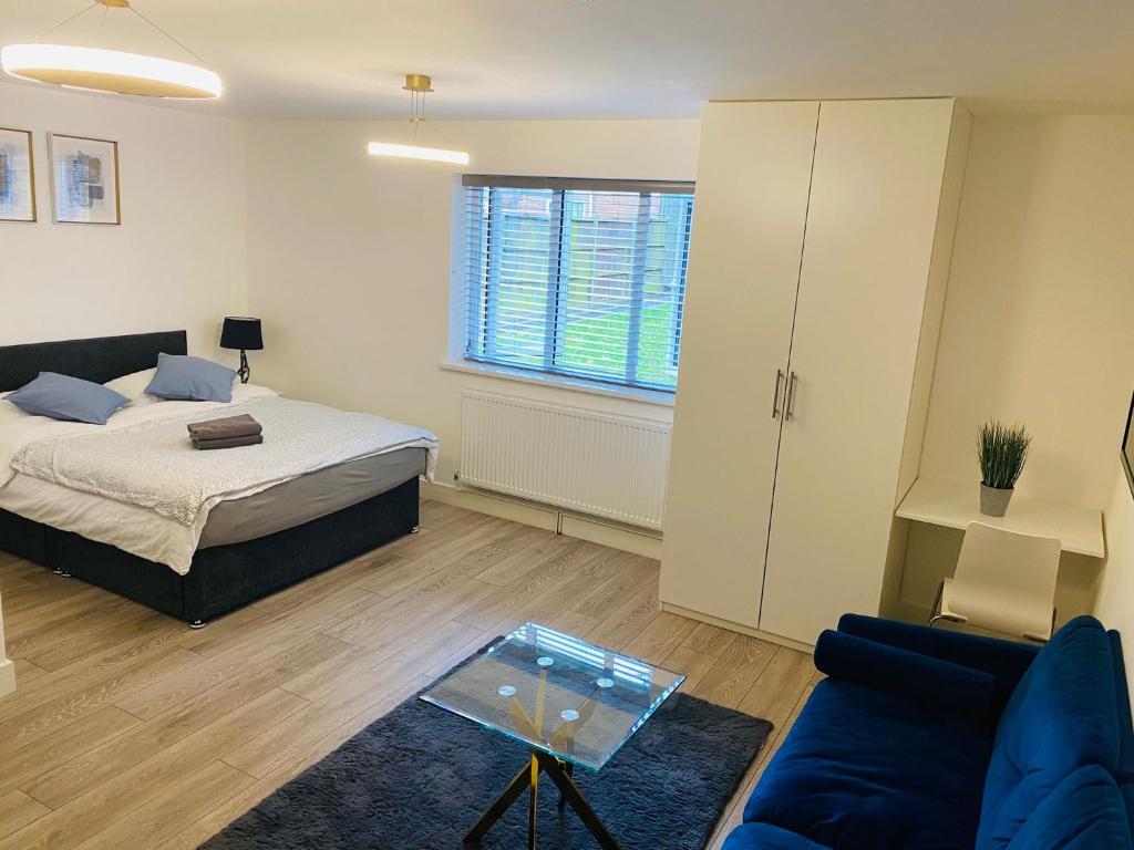 een slaapkamer met een bed, een bank en een tafel bij Roomello luxury City Studios in Peterborough