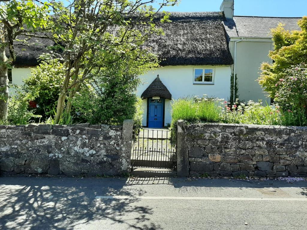 a white house with a blue door and a stone wall at Tawleat in Okehampton