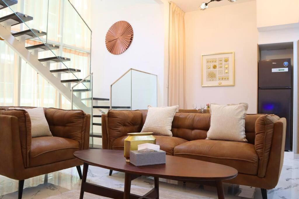 uma sala de estar com um sofá castanho e uma mesa em Duplex Elegance Retreat Transit - 2 BR em Abu Dhabi