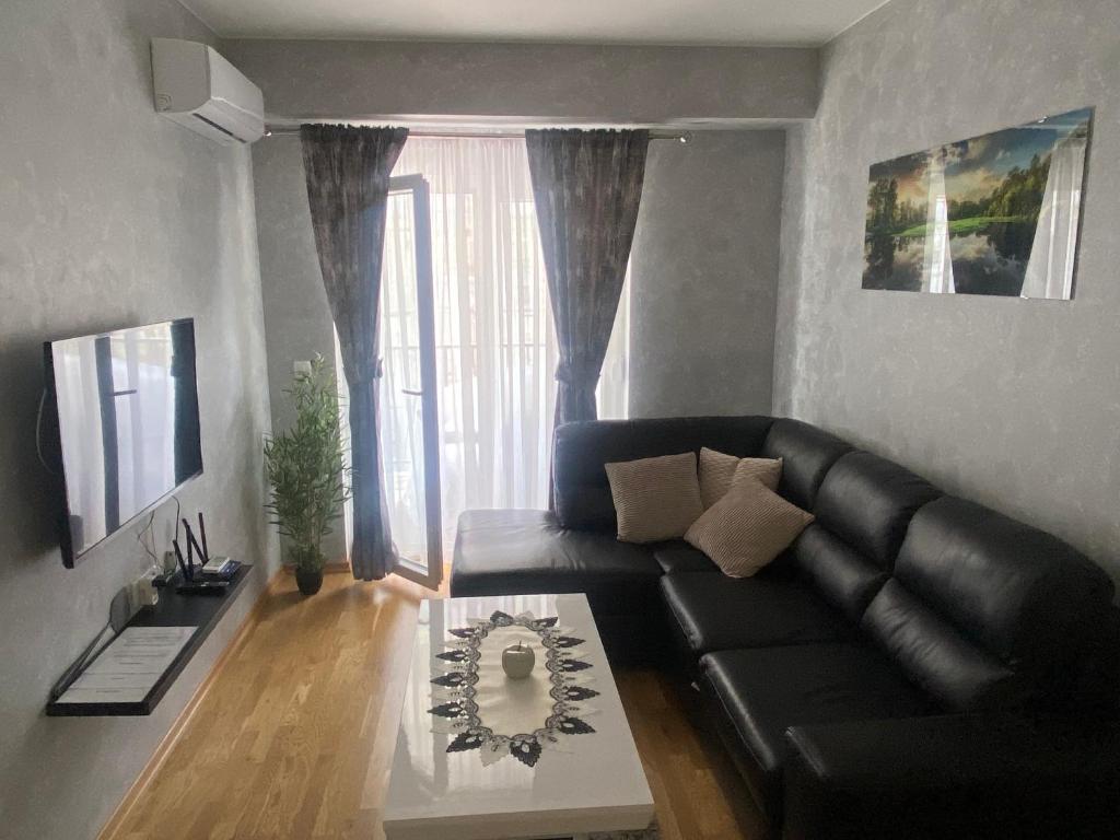 uma sala de estar com um sofá de couro preto e uma mesa em Adriatic apartman em Budva