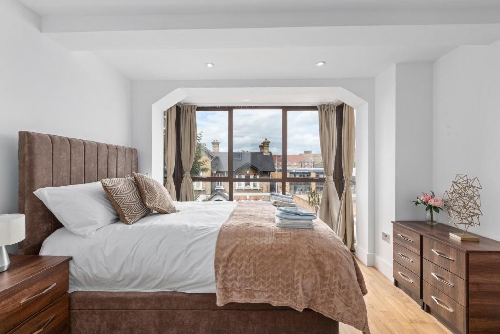 a bedroom with a bed and a large window at Elegant Living in Kingston: Two Bedroom Apartment in Kingston upon Thames