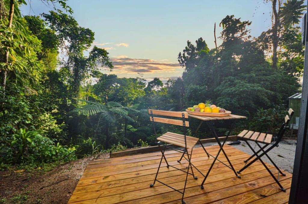una mesa con un bol de fruta en una terraza de madera en Magic Mena Rainforest Retreat en Mena Creek