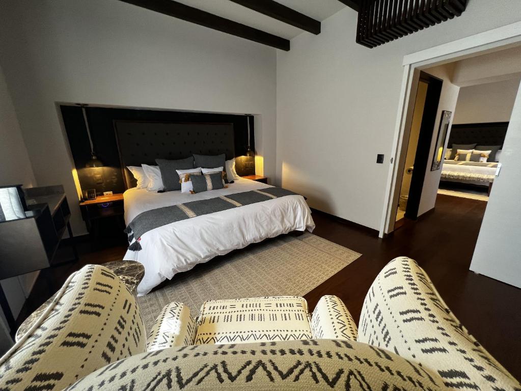 a bedroom with a bed and two pairs of chairs at Casa 63 Hotel Boutique & Spa - Adults Only in San Miguel de Allende