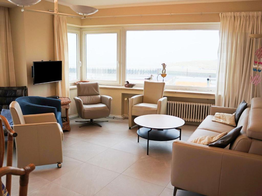 uma sala de estar com sofás e cadeiras e uma grande janela em Scorpio A 0901 with beautiful sea view em Nieuwpoort