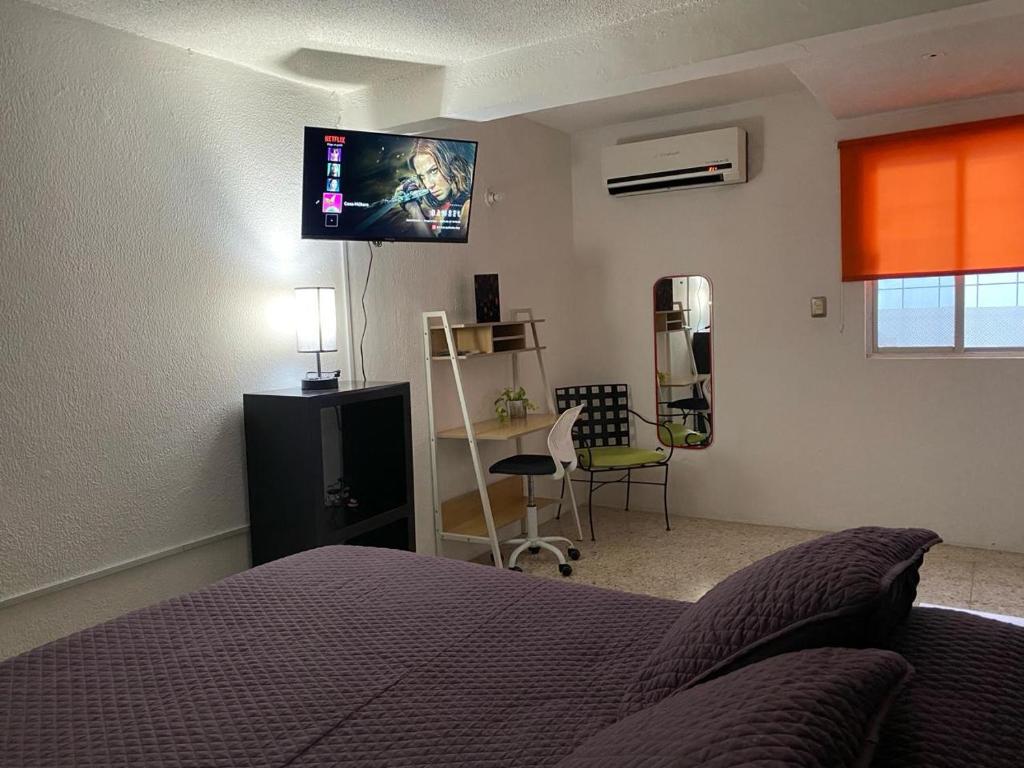 a bedroom with a bed and a flat screen tv on the wall at Casa Múkara del Puerto in Veracruz