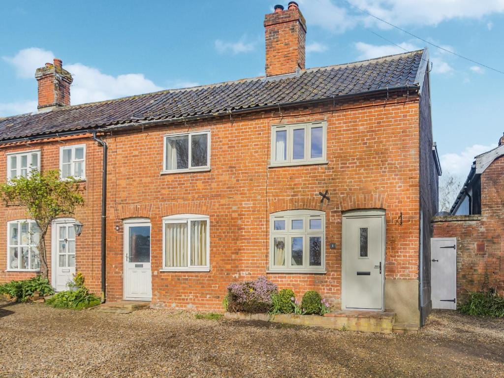 a red brick house with white doors and windows at Buttercup Cottage in Old Buckenham