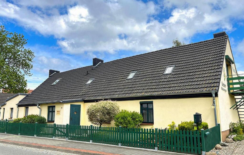 a yellow house with a black roof and a fence at Beautiful Apartment In Ueckermnde seebad With Wifi in Neuendorf