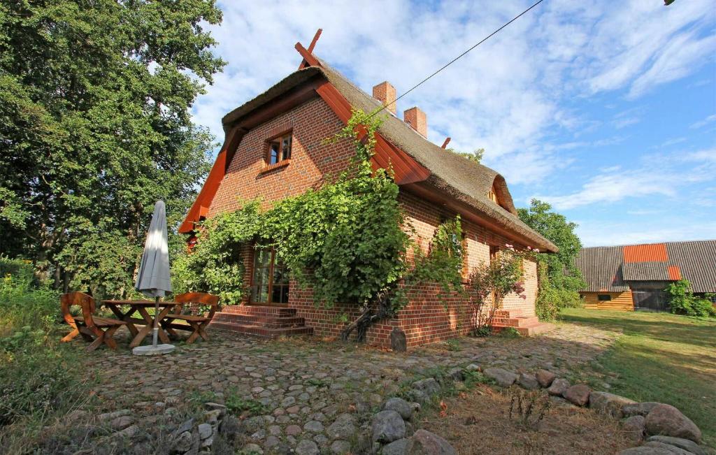 uma pequena casa de tijolos com uma mesa e um guarda-chuva em Stunning Home In Penzlin Ot Krukow With Kitchen em Mallin