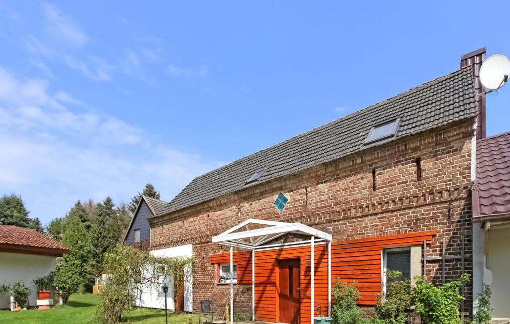 une maison en briques avec une porte orange et un parasol dans l'établissement 1 Bedroom Lovely Apartment In Knigs Wusterhausen Ot, à Kablow