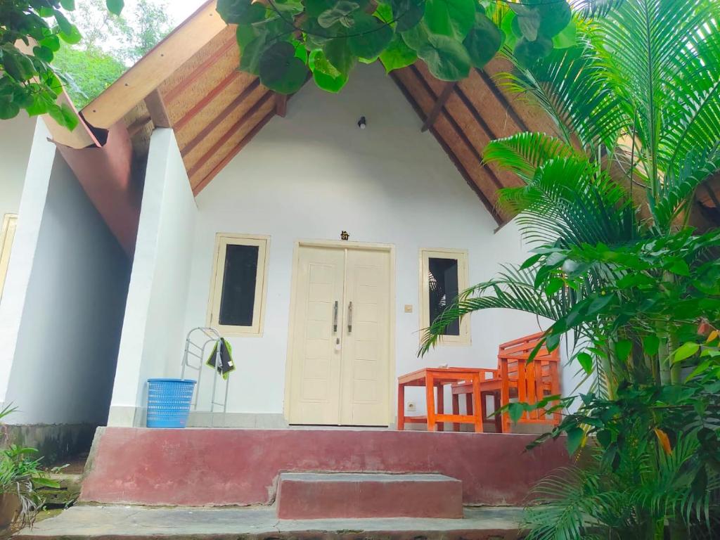 ein kleines weißes Haus mit einem Holzdach in der Unterkunft Putri Nyale Bungalow in Kuta Lombok