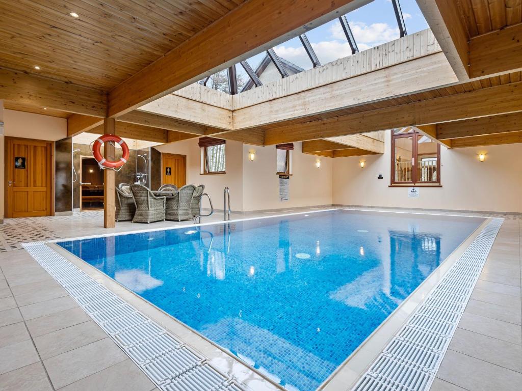 a large swimming pool in a house with a wooden ceiling at Piperdam House in Lundie