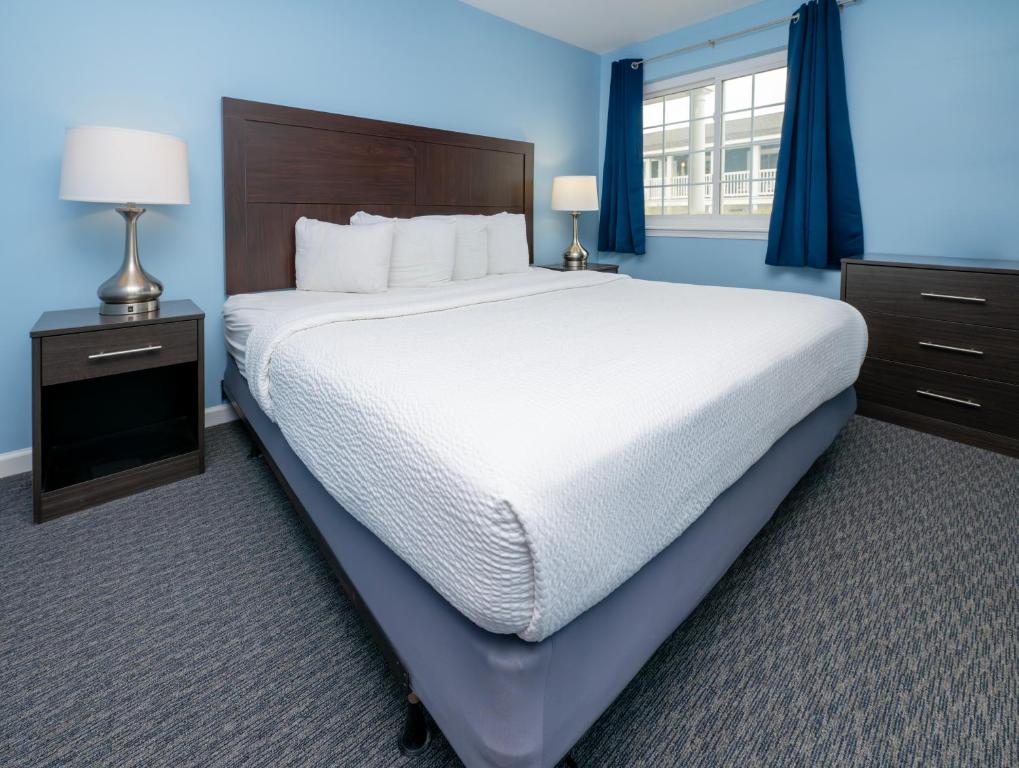 Cama grande en habitación con paredes azules en Commander Beach House Hotel, en Ocean City