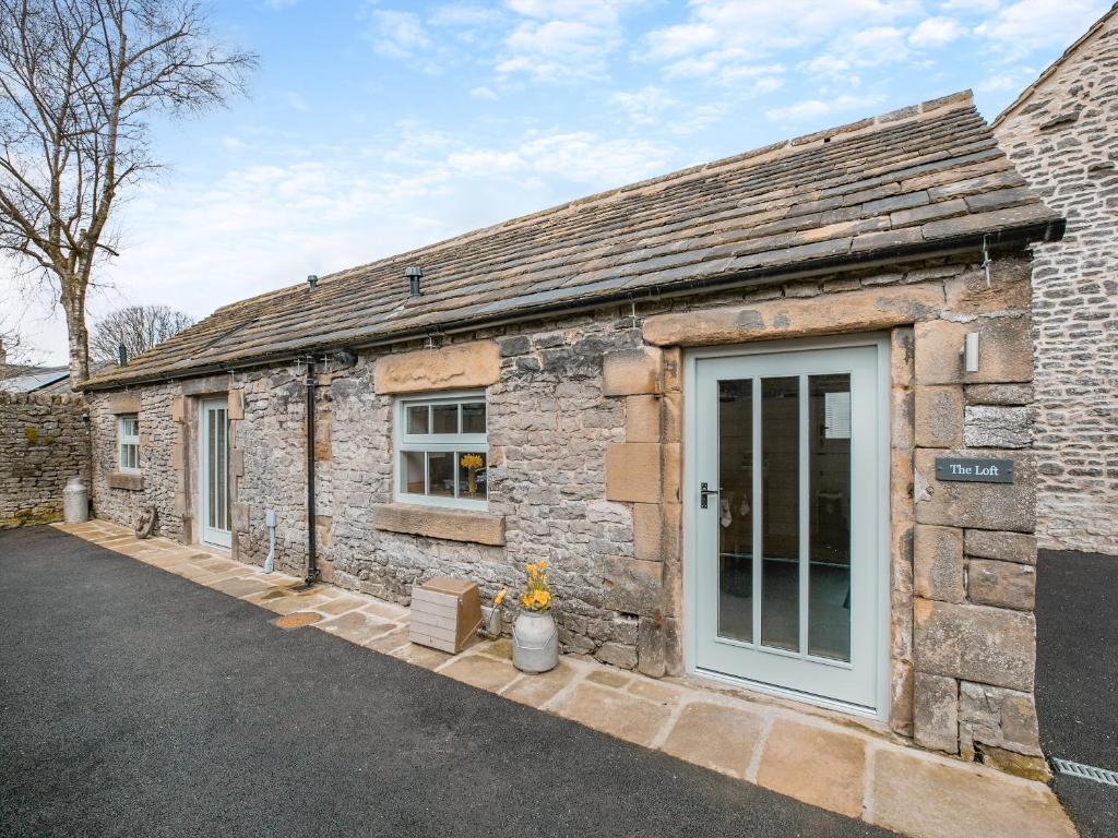an old stone cottage with a front door at The Loft-uk45061 in Tideswell