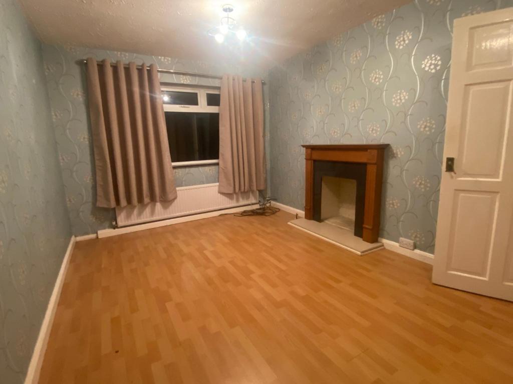 an empty living room with a fireplace and a window at Maidenhead house in Maidenhead