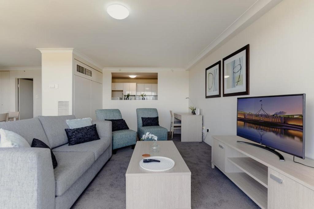 sala de estar con sofá y TV en 2-Bed with Gym, Tennis Court & Stunning Lake Views, en Canberra