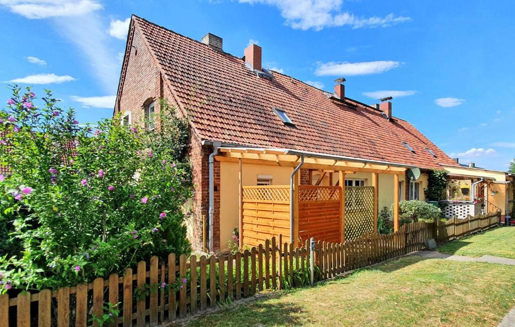 a small yellow house with a wooden fence at 2 Bedroom Nice Apartment In Grabowhfe Ot Sophienh 