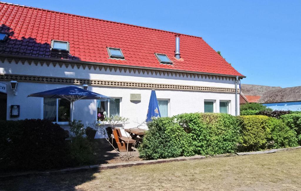 a white house with a red roof with a table and an umbrella at Cozy Apartment In Meiersberg With Kitchen in Meiersberg